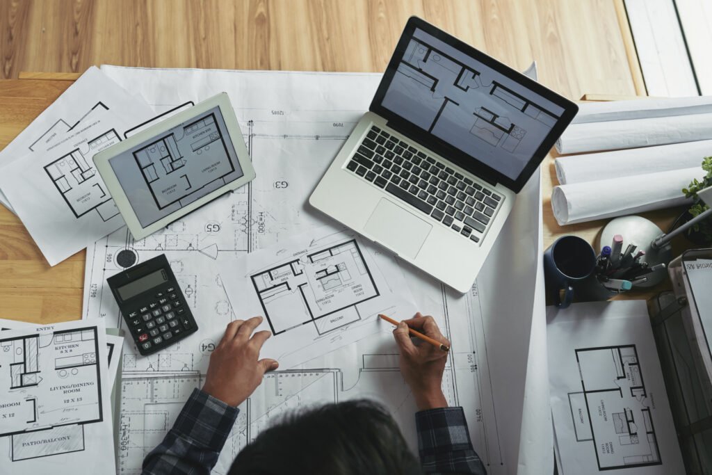 Professional architect making corrections in apartment blueprint, view from above